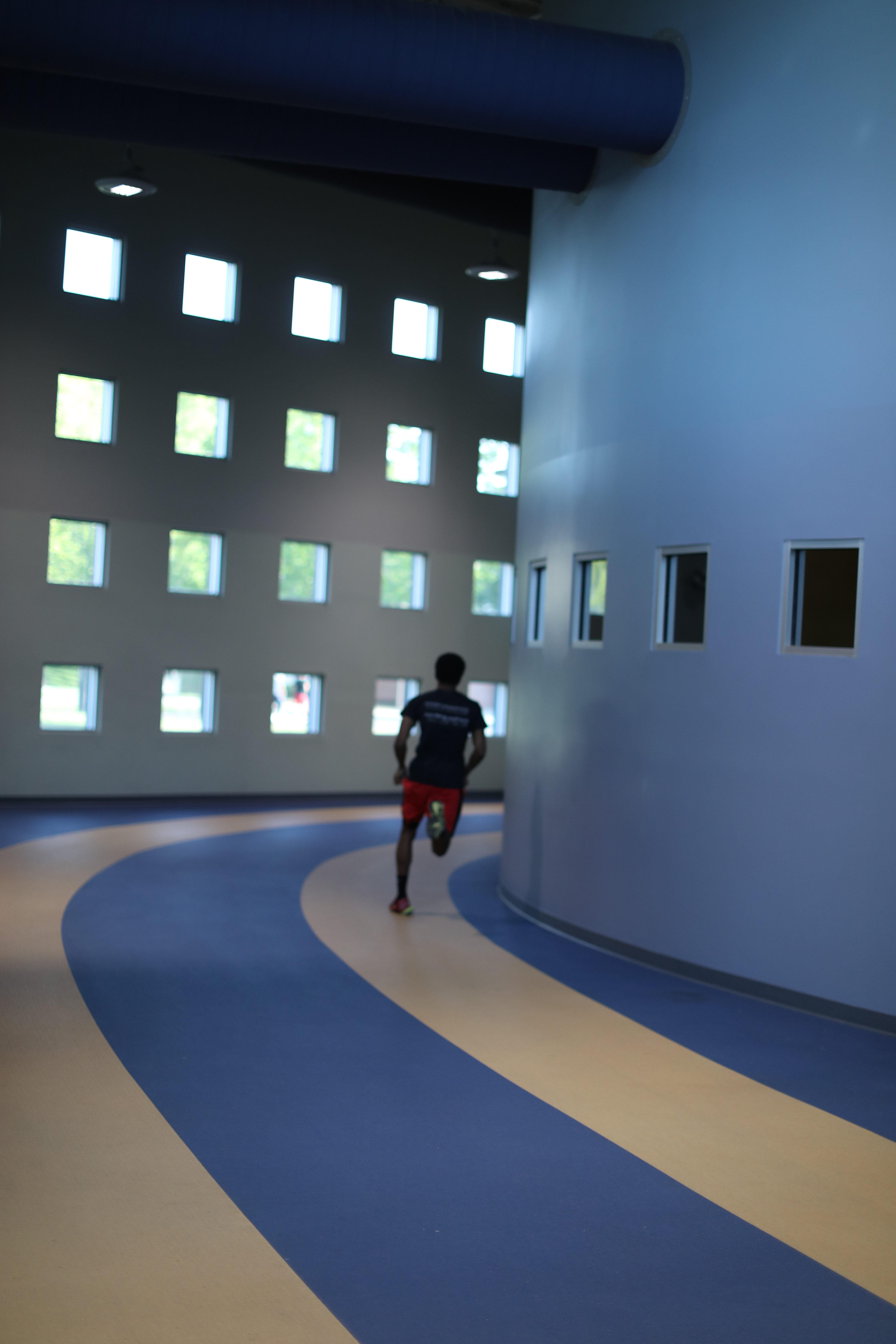  an a and t student runs on an indoor track - Campus Recreational Center